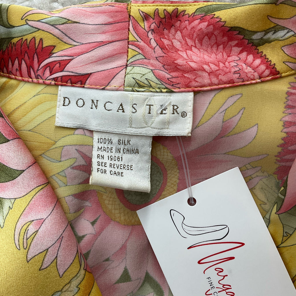 Close-up of Doncaster brand label on yellow/pink floral silk top, size small, highlighting 100% silk material and consignment fashion appeal.
