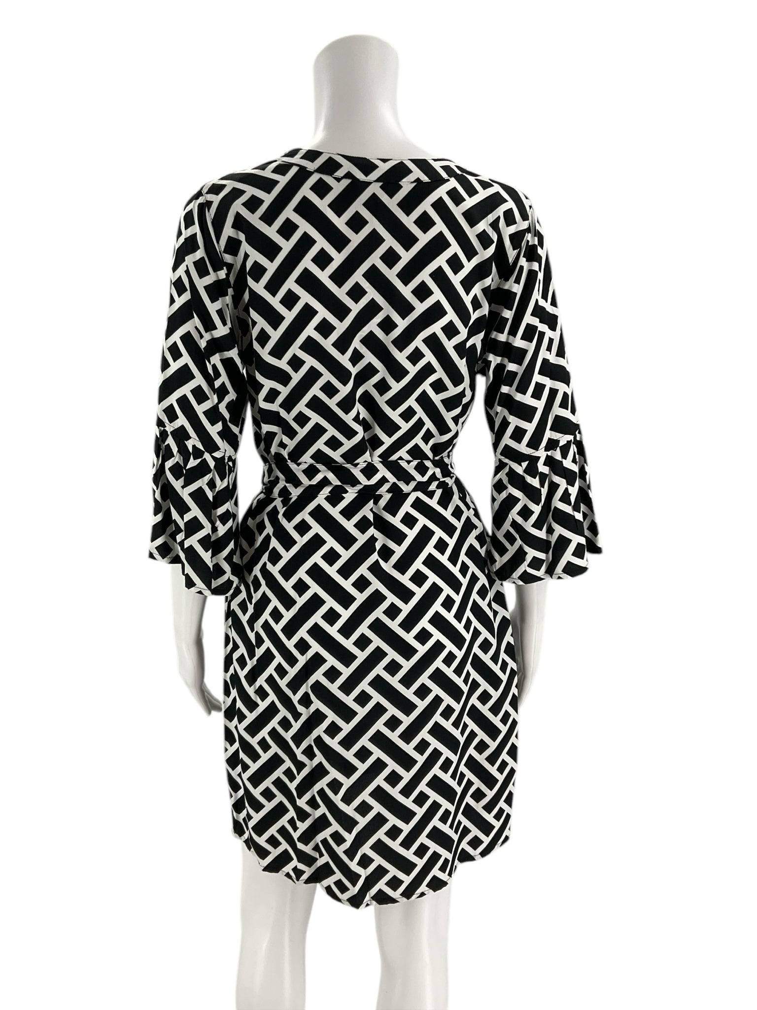 Back view of Escapada Dress Size Small in black and white geometric pattern, showcasing tie waist and ruffled sleeve detail.