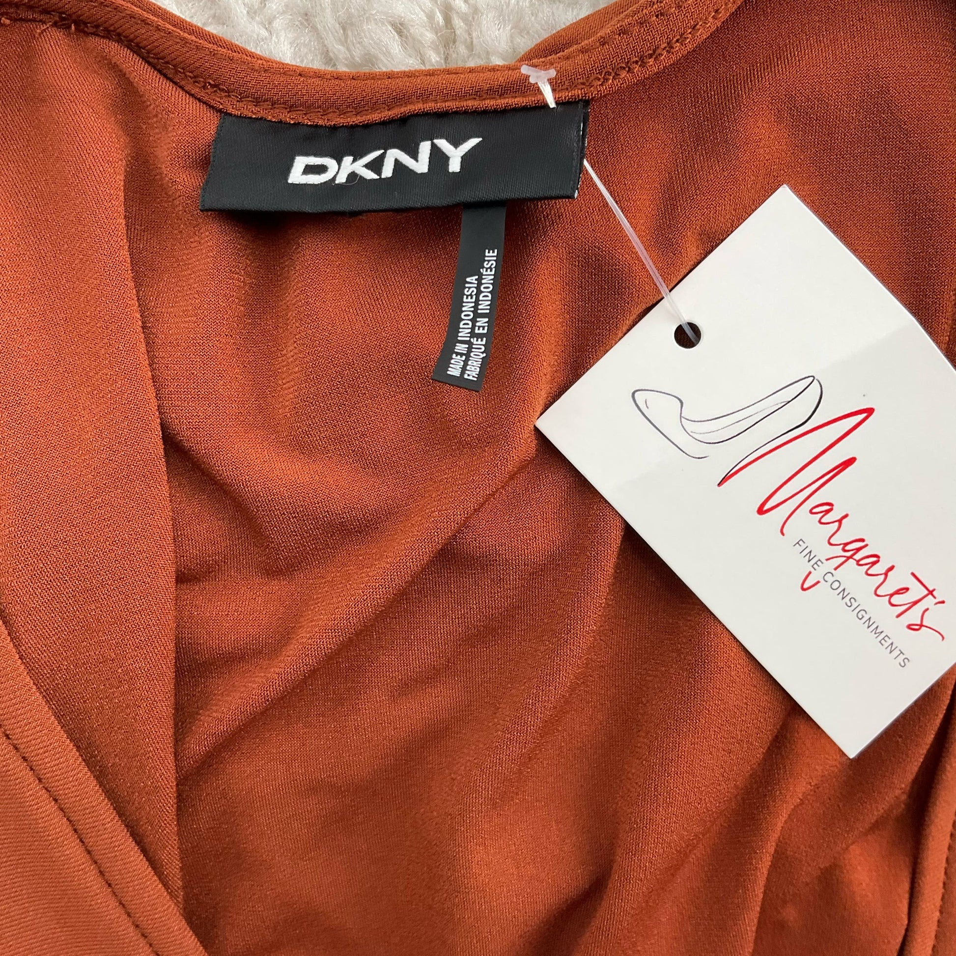 Close-up of DKNY label and Margaret’s Fine Consignments tag on Burnt Orange Pre-Owned Dress - Size XL, confirming authenticity.