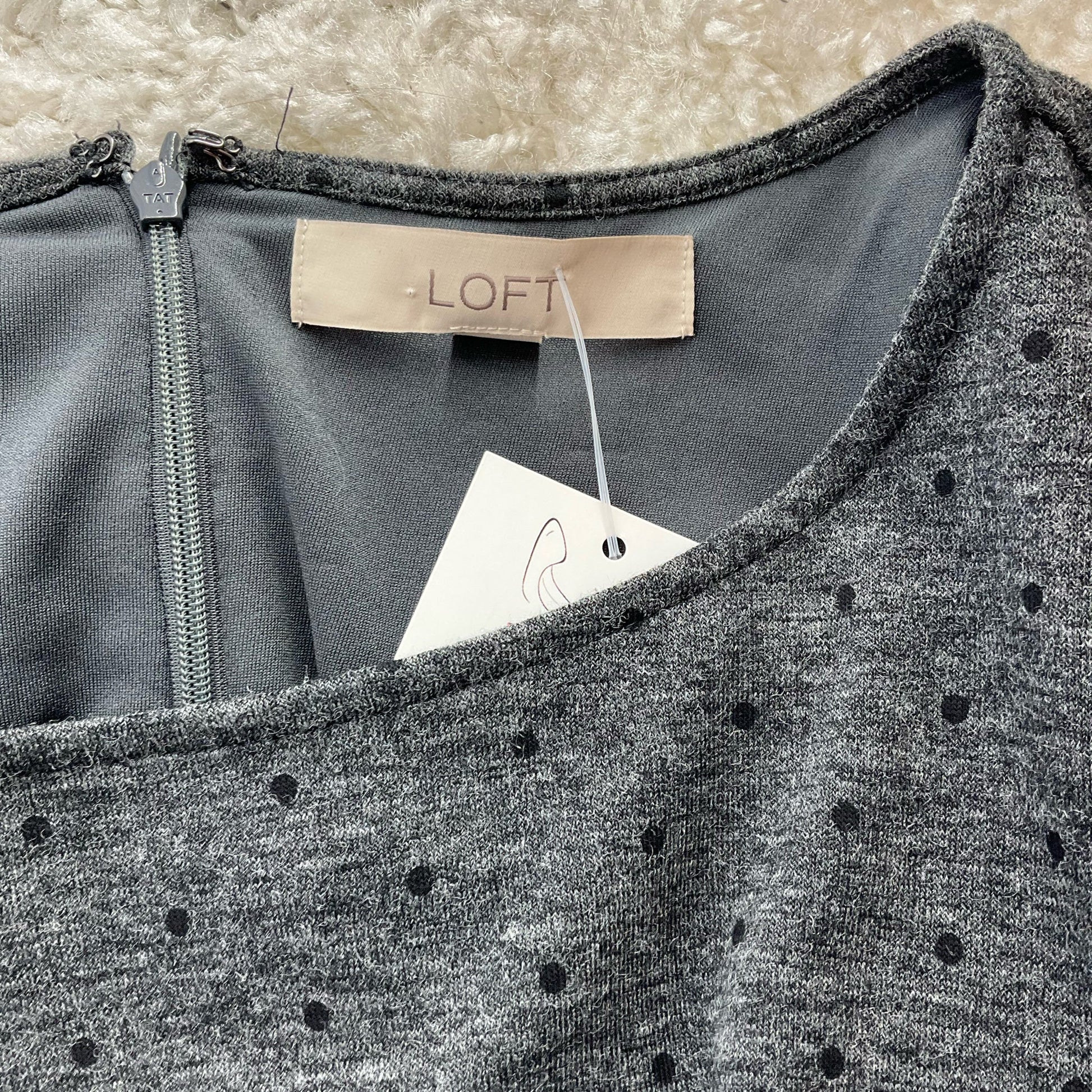 Close-up of Loft label and tag on Gray/Black Polka Dot Pre-Owned Dress - Size Medium, confirming brand authenticity and condition.