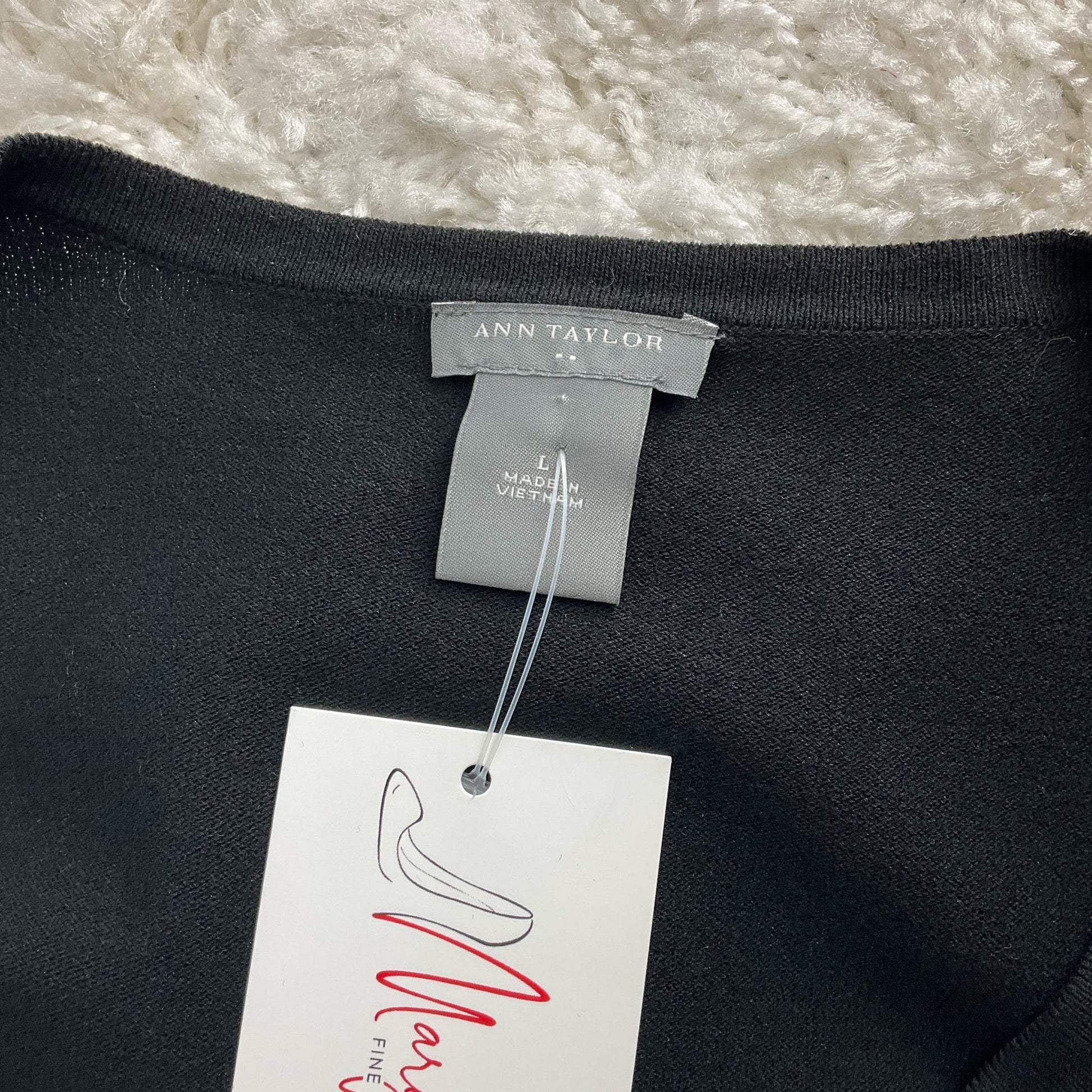 Close-up of Ann Taylor label on black shrug, size L, confirming brand and size for pre-owned women's apparel listing.