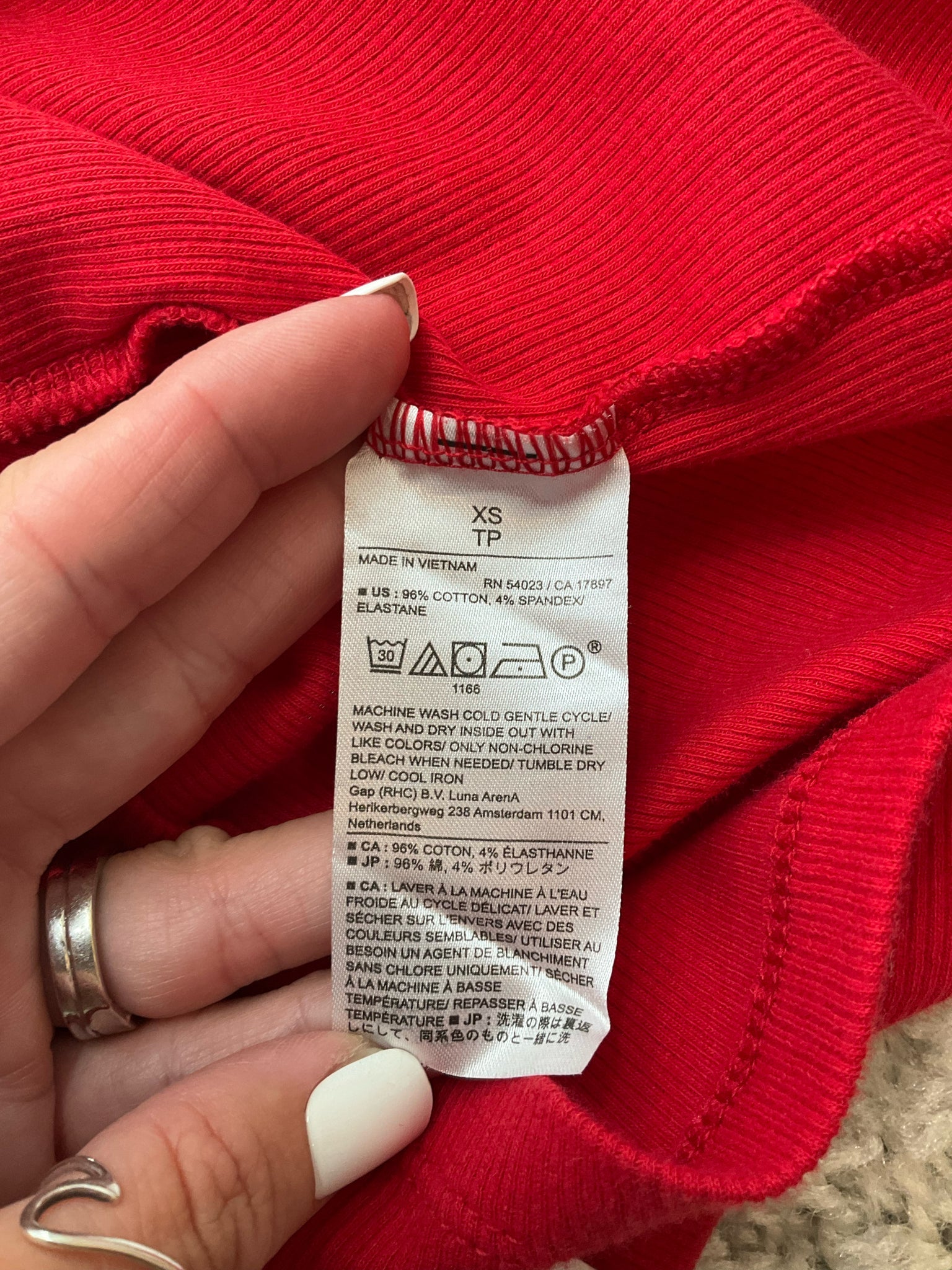 Fabric care label of Banana Republic red ribbed tank top, size XS. Made of 96% cotton and 4% spandex for a soft, stretchy fit.