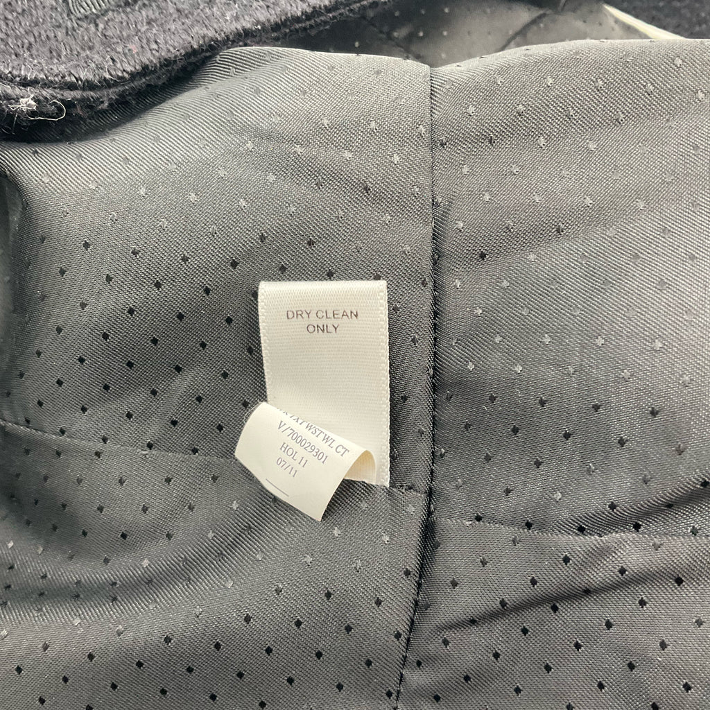 Close-up of care label on Banana Republic Black Textured Wool-Blend Coat – Size XS indicating dry clean only instructions for fabric maintenance.