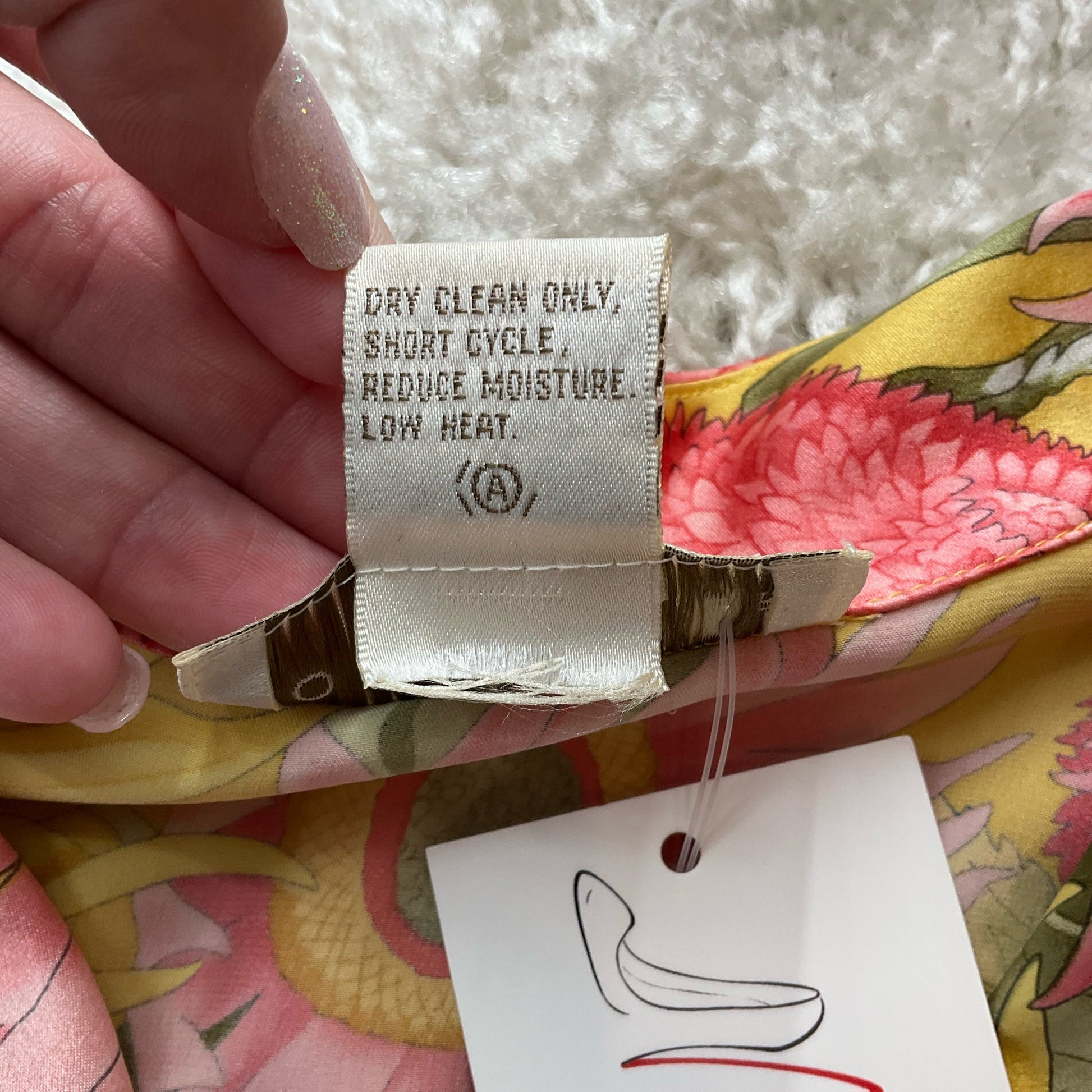 Care label on Doncaster Silk Floral Top, size small, indicating dry clean only instructions for maintaining luxury silk fabric quality.
