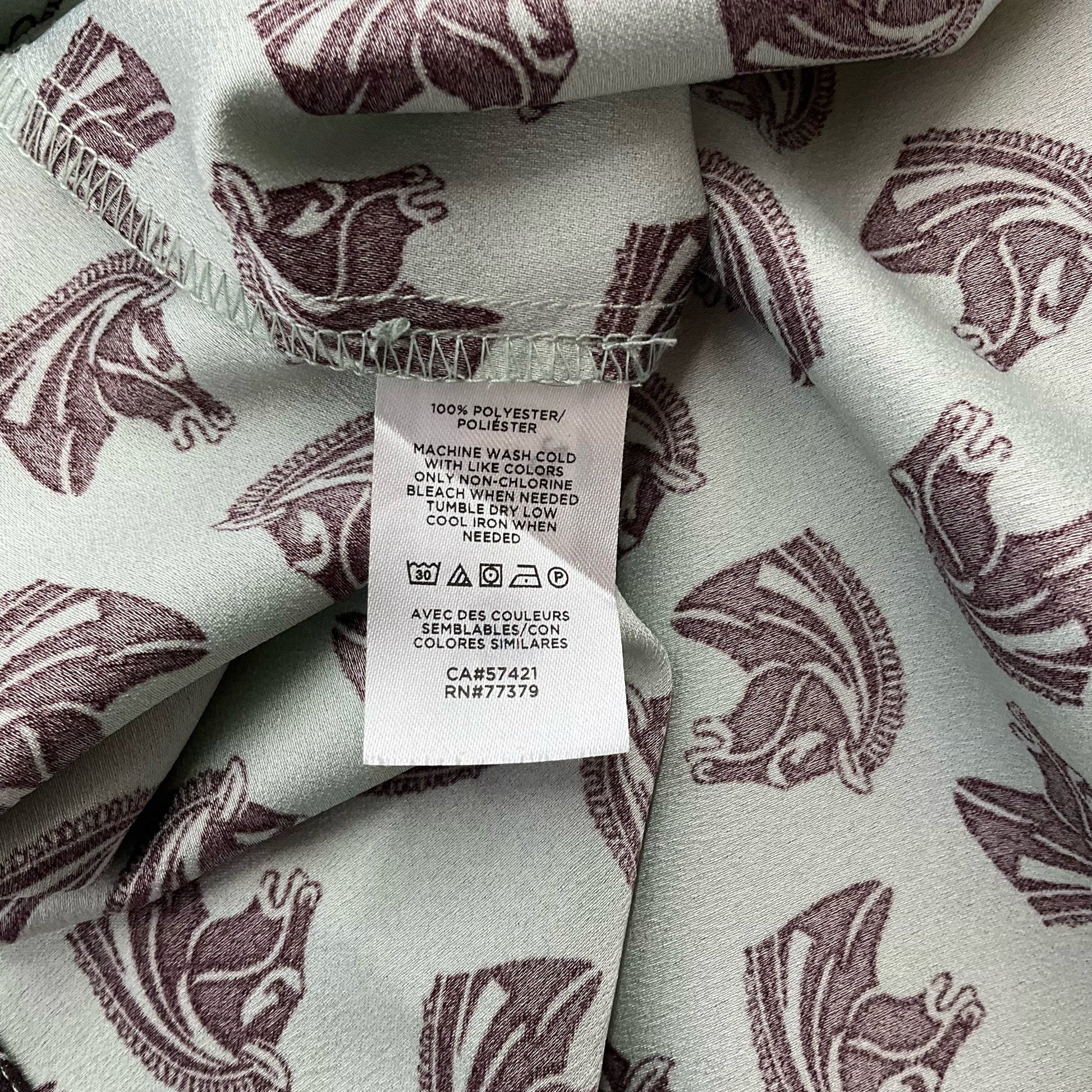 Fabric care label of Ann Taylor Mint/Maroon Pre-Owned Top - Size Large showing 100% polyester material and washing instructions.