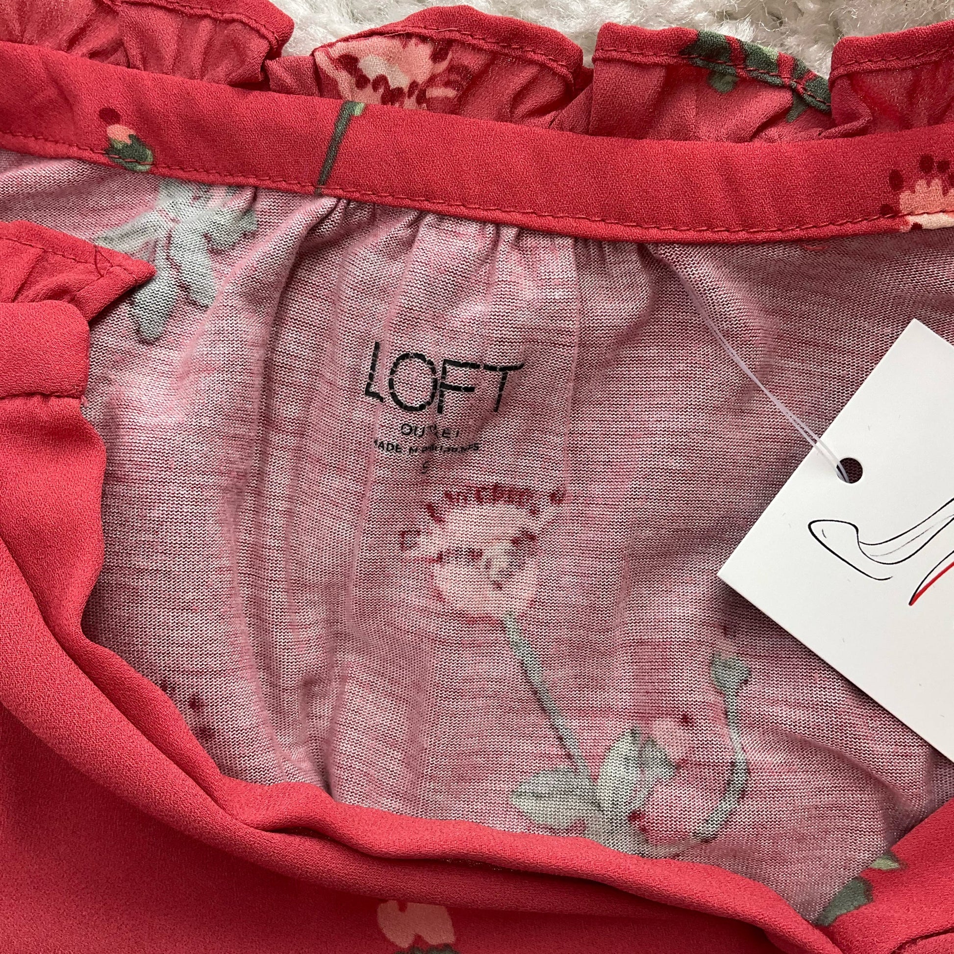Close-up of Loft brand label inside red floral blouse, confirming authenticity and pre-owned status, size small.