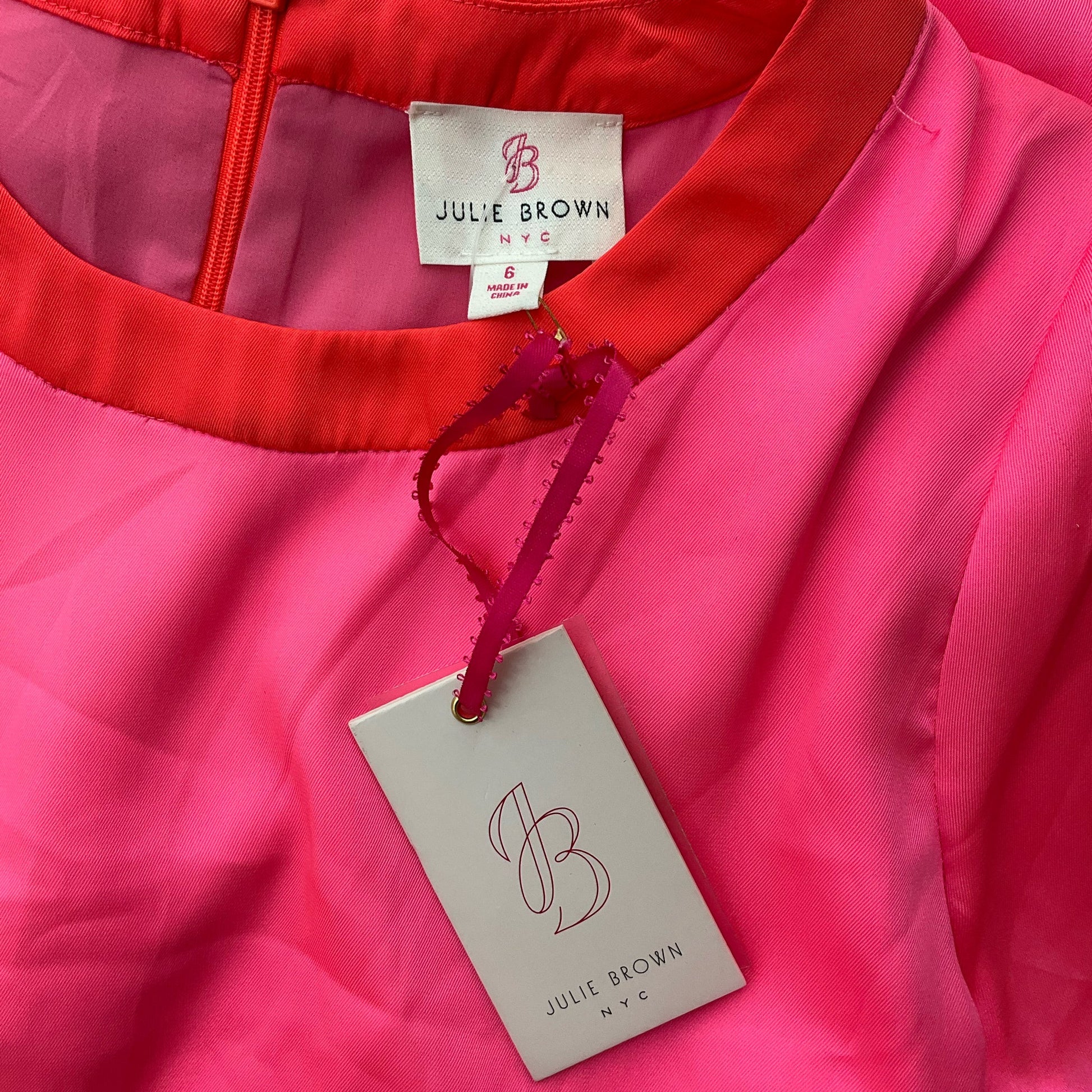 Close-up of Julie Brown NYC brand tag on pink dress, size 6. Shows original hang tag confirming new with tags condition.