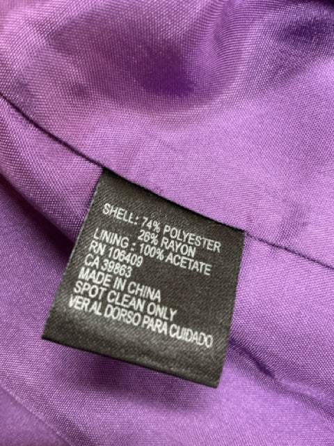 Close-up of care label on Antonio Melani purple dress showing fabric composition of 74% polyester and 26% rayon, spot clean only.
