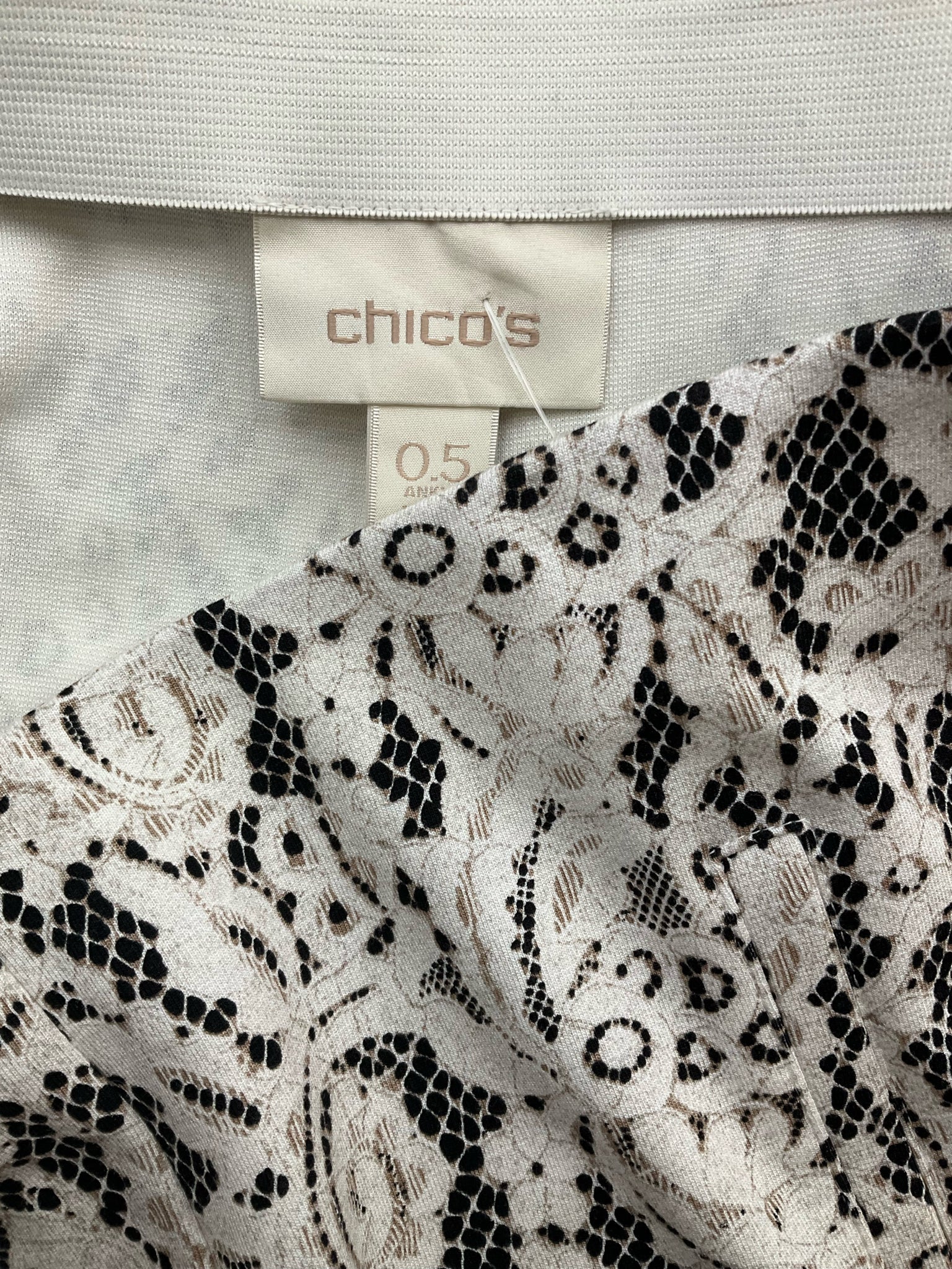 Chico's cream and black lace pull-on ankle pants, tapered leg, stretch knit, size small, laid flat on a surface.