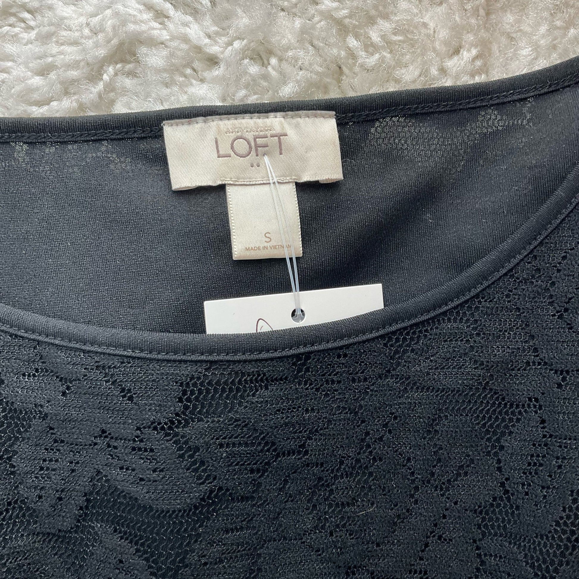 Close-up of Loft brand tag on Black Lace Pre-Owned Top - Size Small, confirming size and authenticity for resale fashion.