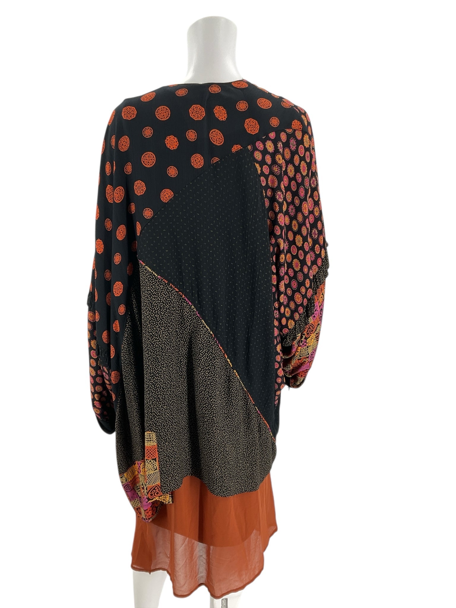 Back view of black, orange, and pink printed shrug with mixed patterns, loose fit, pre-owned women's sweater, one size fits most.