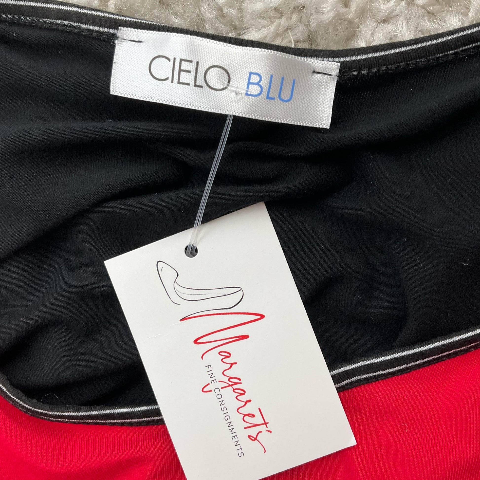 Close-up of Cielo Blu brand label and consignment tag on red/black women's top, size small, highlighting authenticity and resale quality.