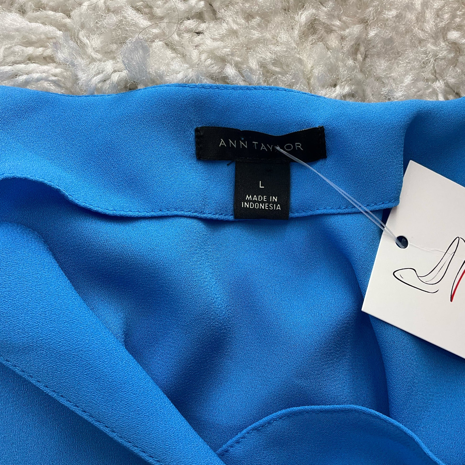 Close-up of Ann Taylor label and size tag on Blue Solid Pre-Owned Top - Size Large, confirming authenticity and origin.