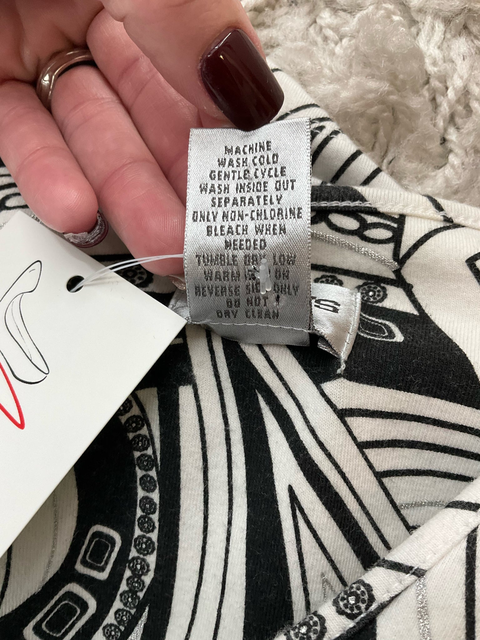 Chico's pre-owned white and black print V-neck pullover top for ladies in size medium displayed on a hanger.