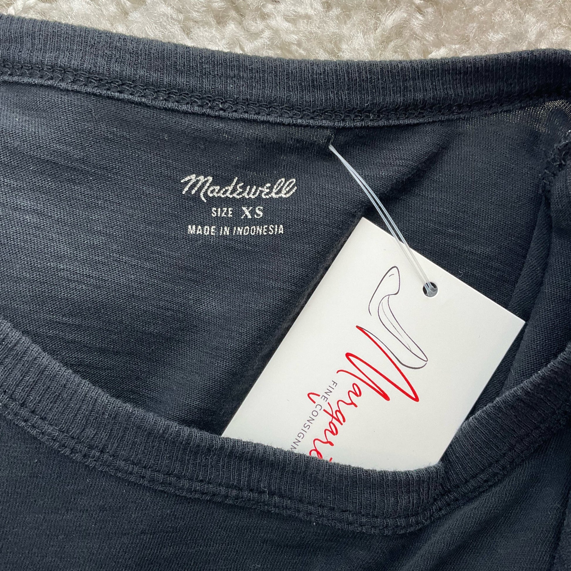 Close-up of Madewell blouse label showing size XS and tag, confirming authenticity and pre-owned condition.