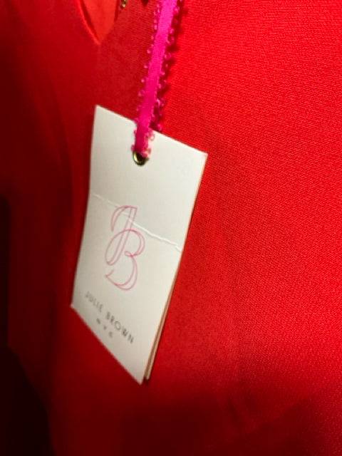 Close-up of Julie Brown brand tag attached to red dress, confirming new with tags status. Available at Margaret’s Fine Consignments.