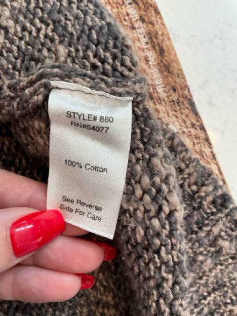 Close-up of fabric tag on Cabi Shrug Size XL showing 100% cotton material. High-quality knitwear from Margaret’s Fine Consignments.