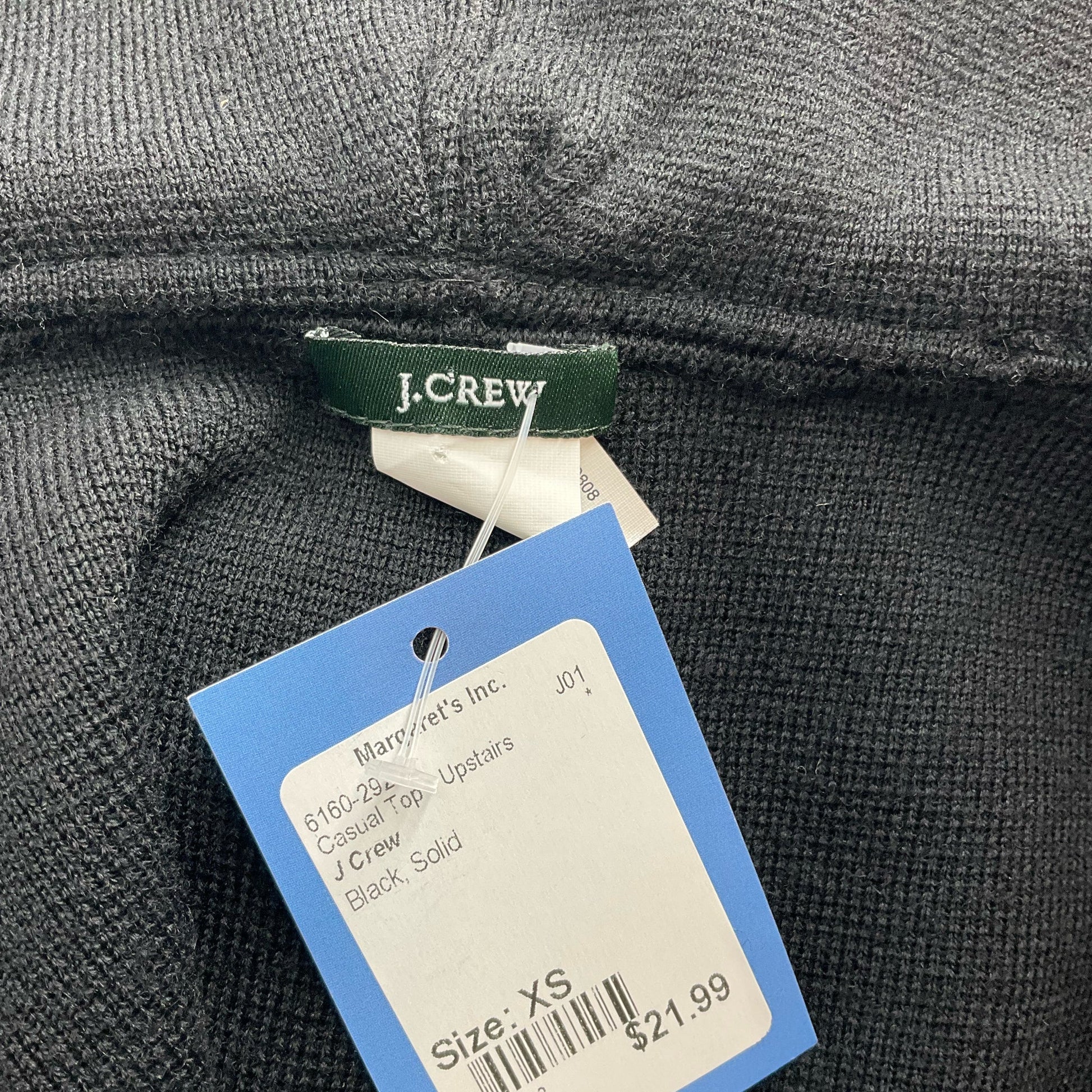 Close-up of J Crew label and price tag on Black Solid Pre-Owned Top - Size XS, marked at $21.99 for sustainable fashion.