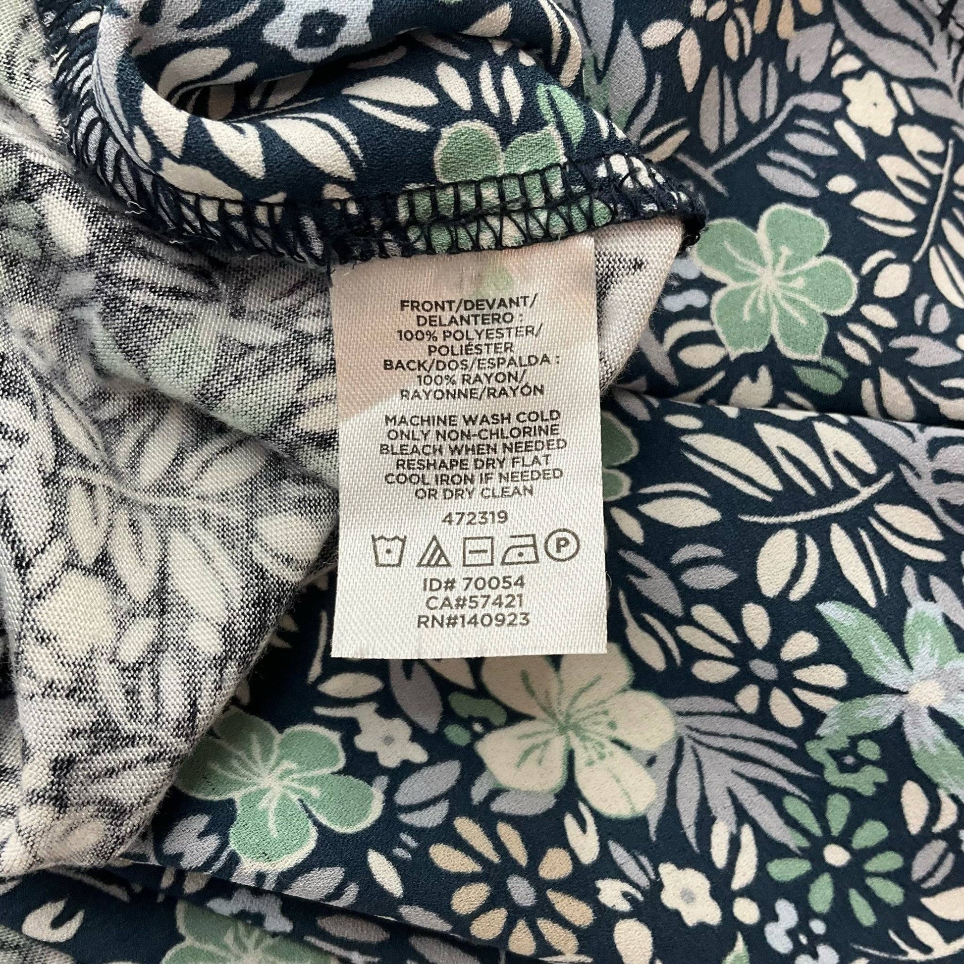 Fabric care label of Loft Navy/Multi Floral Blouse - Size Small showing material composition and washing instructions for proper maintenance.