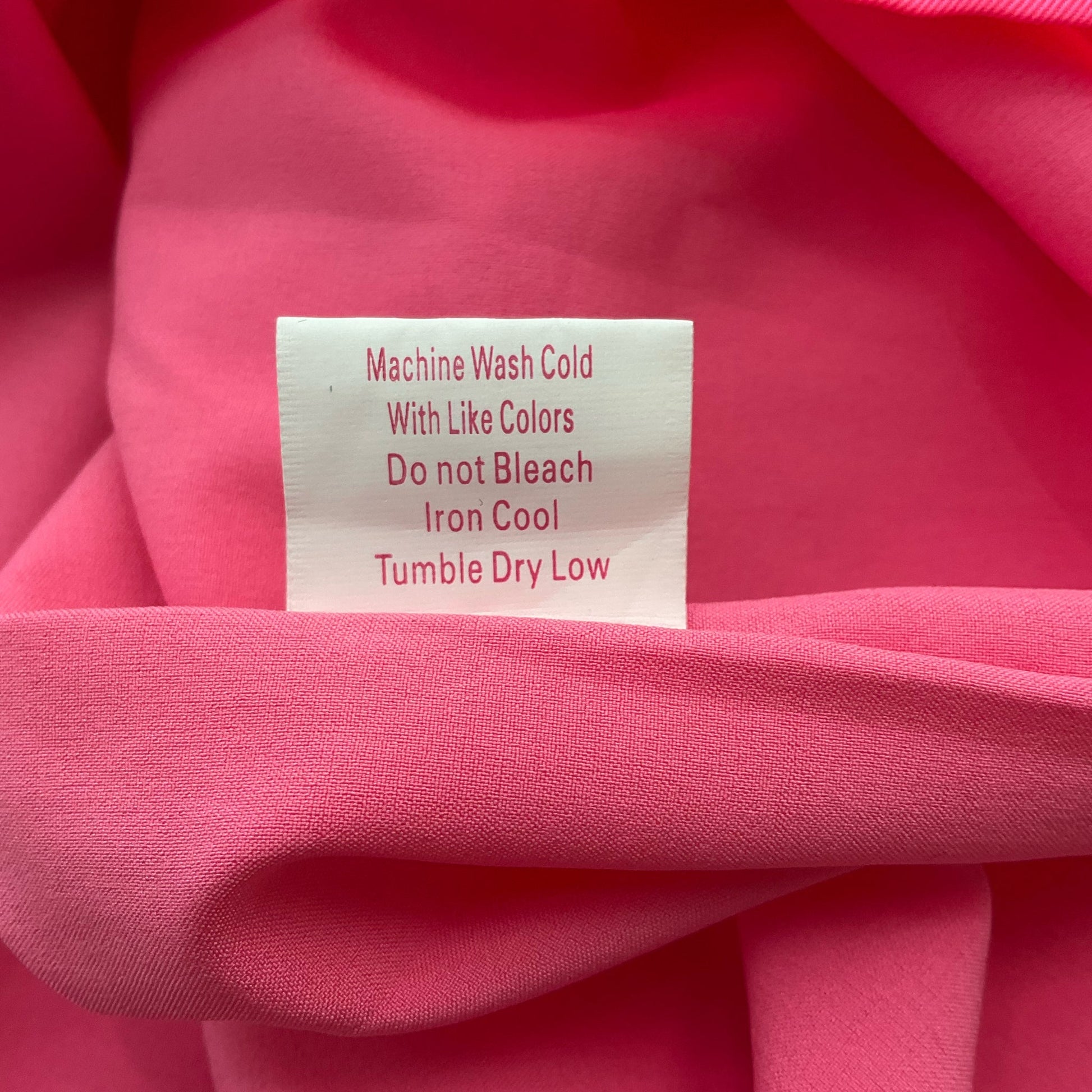 Care label on Julie Brown pink dress, size 6. Machine washable with cool iron and tumble dry low instructions.